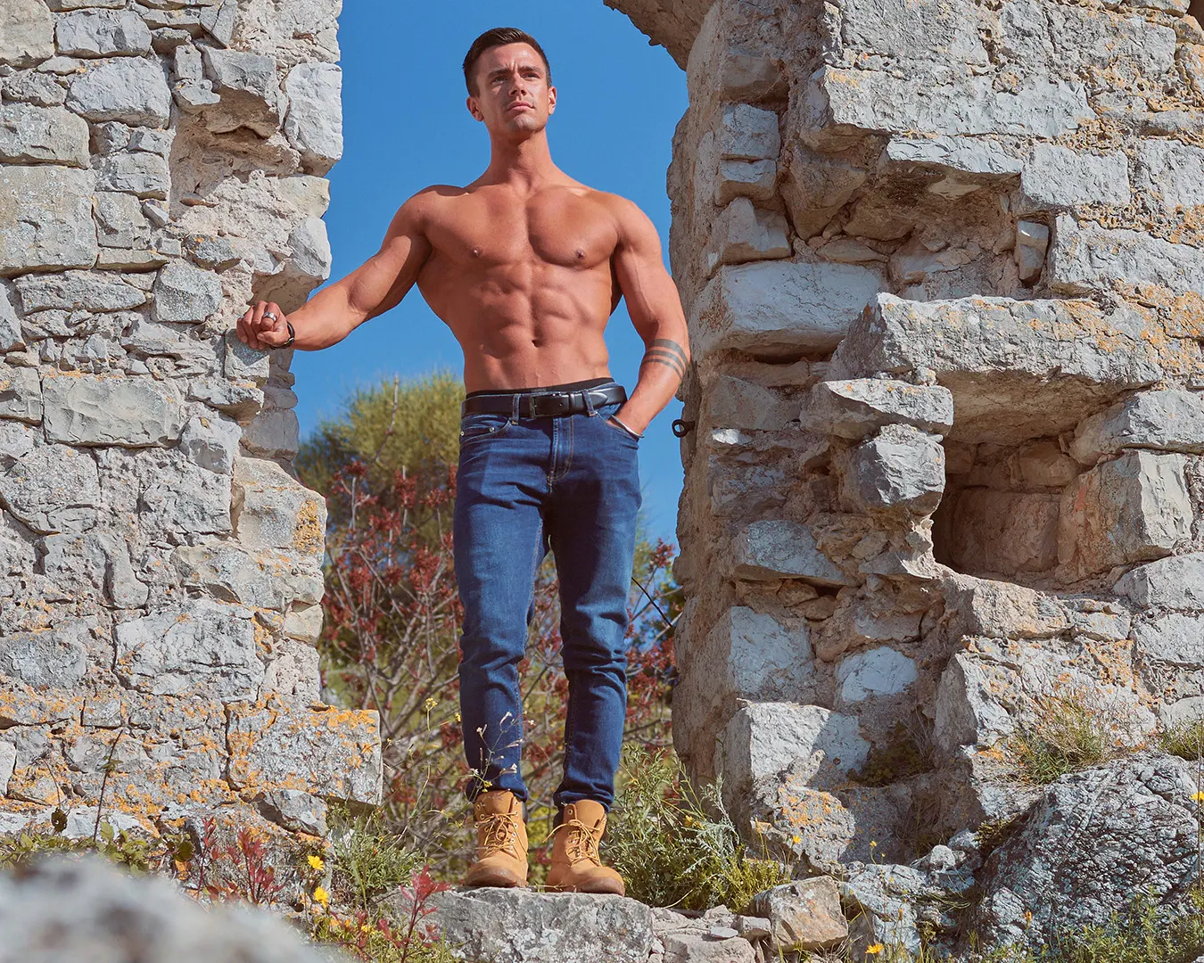 Athlète masculin torse nu et musclé posant dans des ruines de pierre, séance photo fitness en extérieur sur la Côte d'Azur