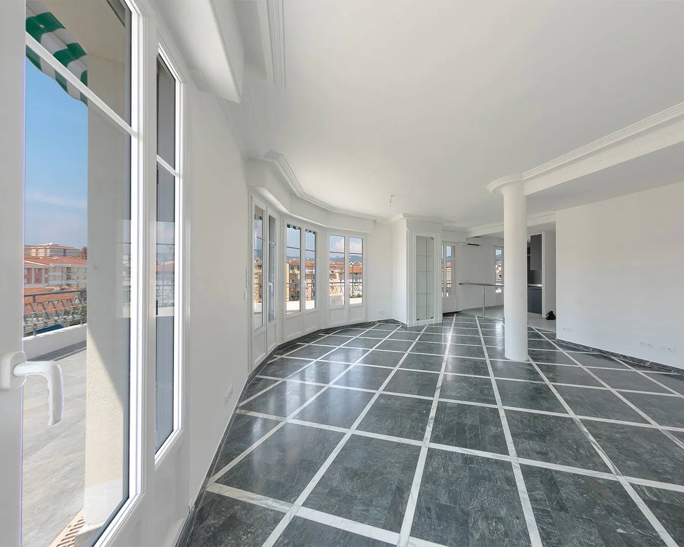 Vaste séjour lumineux d'un appartement de standing, sol en marbre et baies vitrées, photographie immobilière Côte d'Azur
