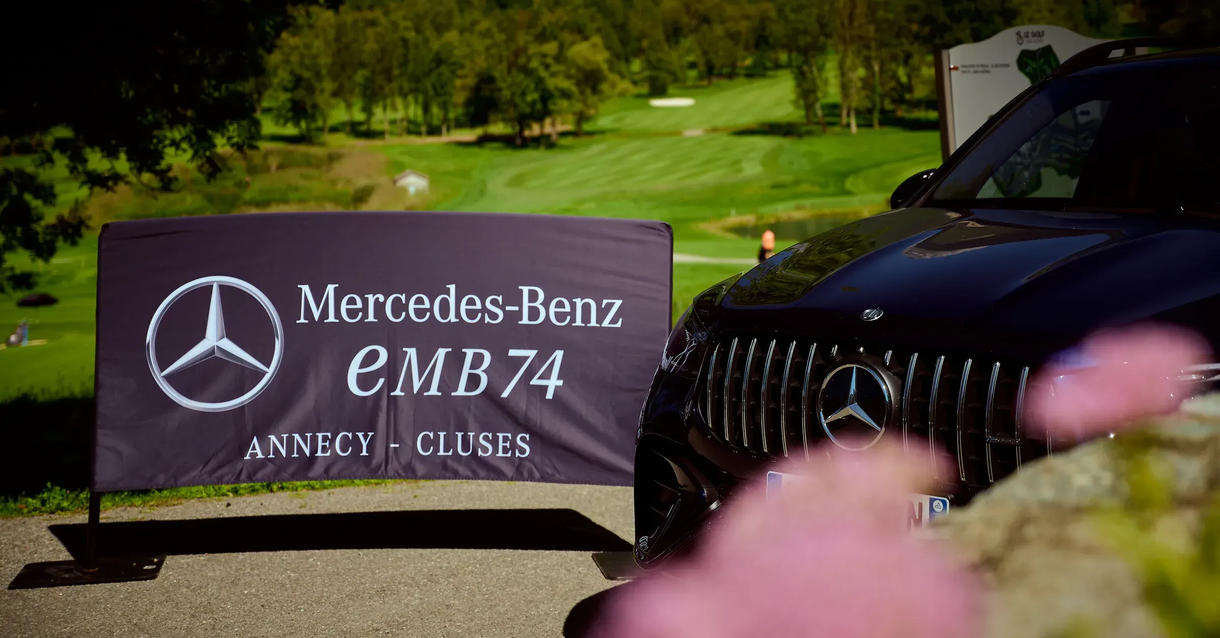 Calandre d'un SUV Mercedes-Benz AMG noir près d'une bannière EMB, sur le parcours du Golf des Alpes à Giez, photographie automobile