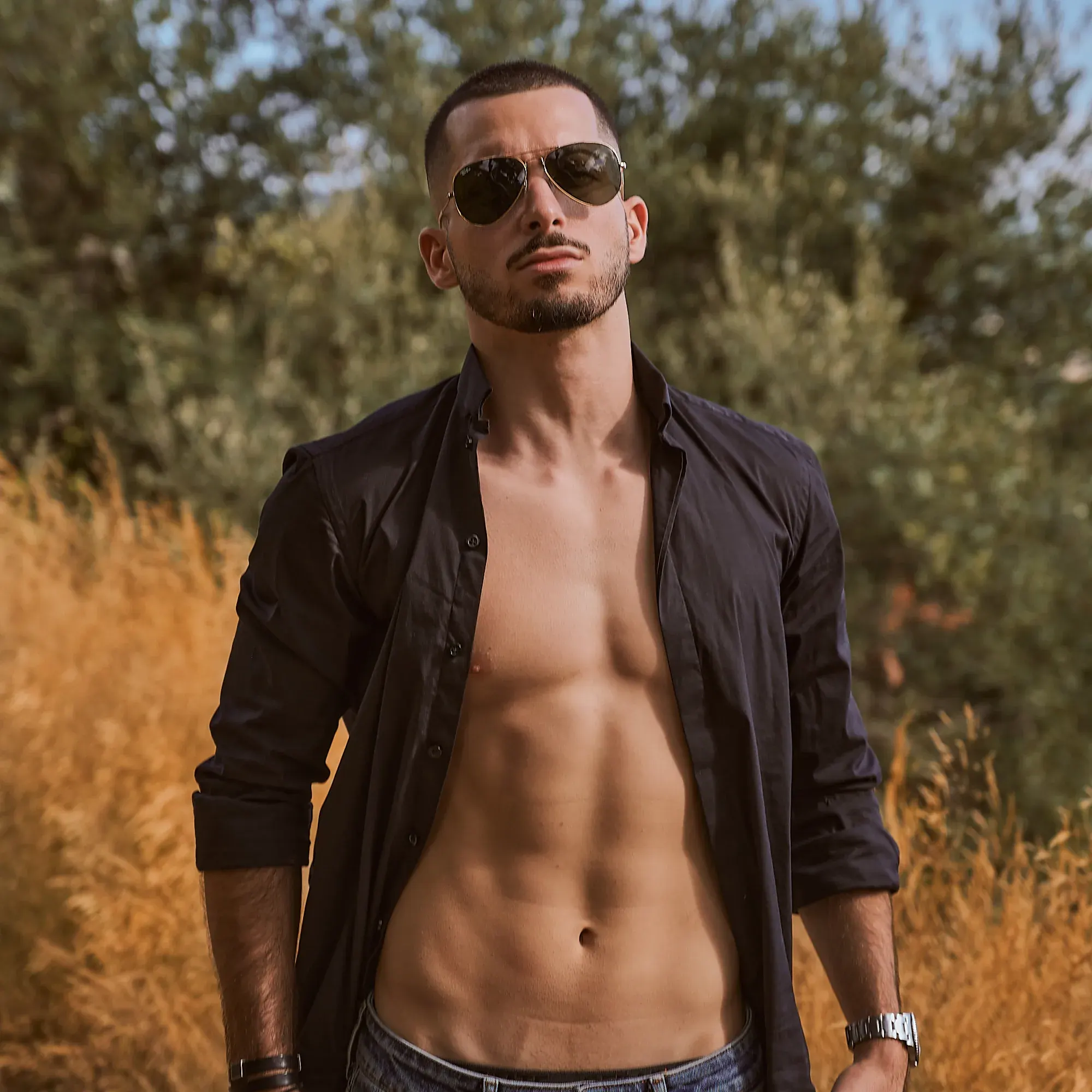 Coach sportif, chemise noire ouverte sur des abdominaux dessinés, lunettes aviateur, herbes dorées, photographe fitness Suisse romande & France