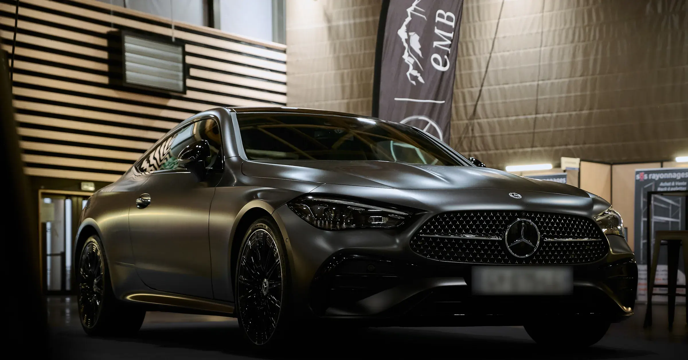 Coupé Mercedes-Benz CLE gris mat aux jantes noires exposé sous drapeau EMB, photographe automobile à La Roche-sur-Foron