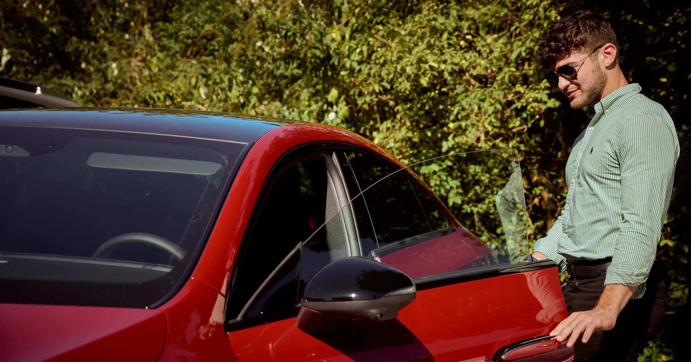 Homme en chemise rayée ouvrant la portière d'un coupé rouge aux vitres sans cadre à Giez, photographie automobile