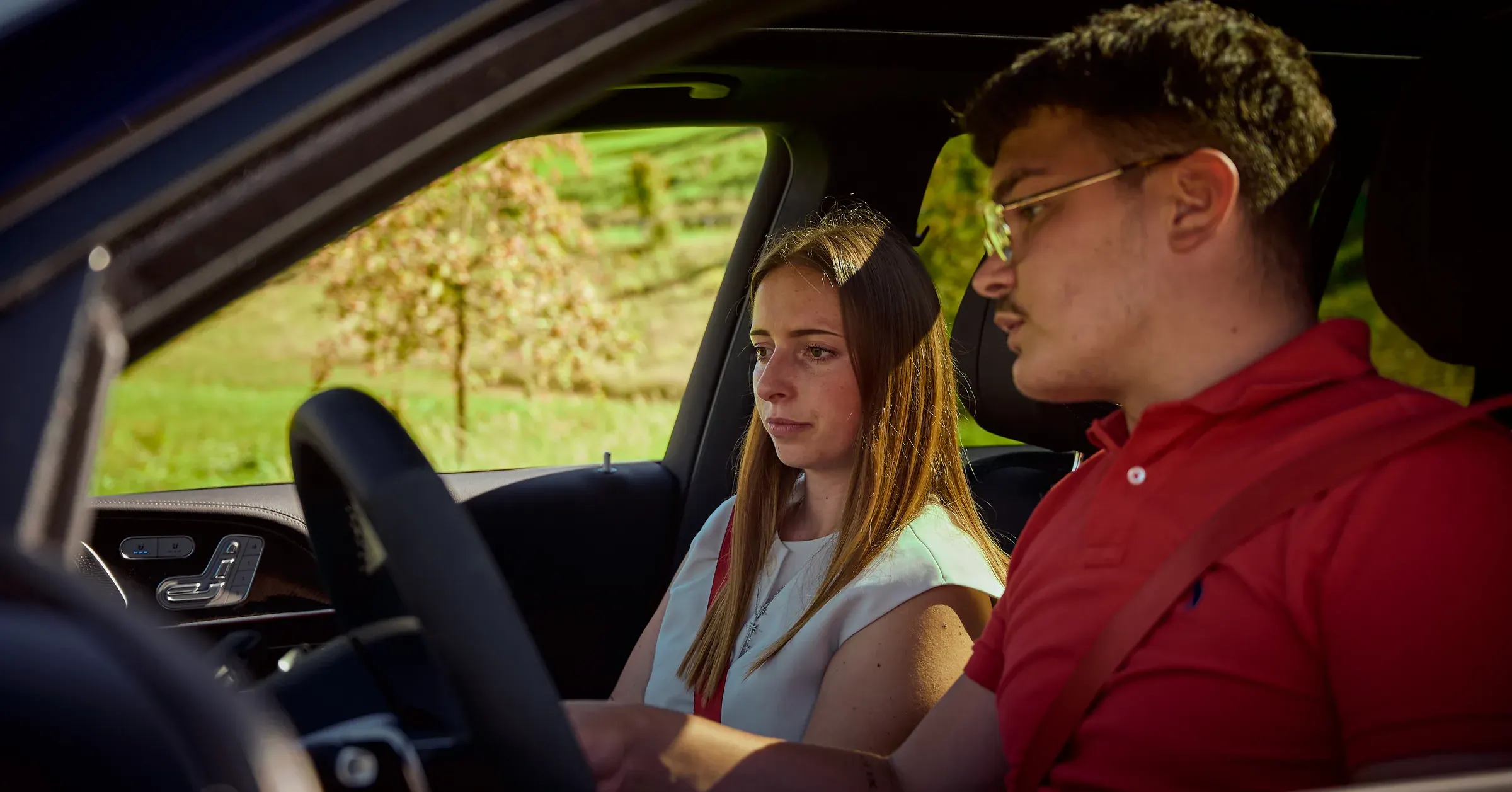 Jeune femme passagère et conducteur en polo rouge à bord d'un SUV premium, photographie automobile au Golf des Alpes à Giez