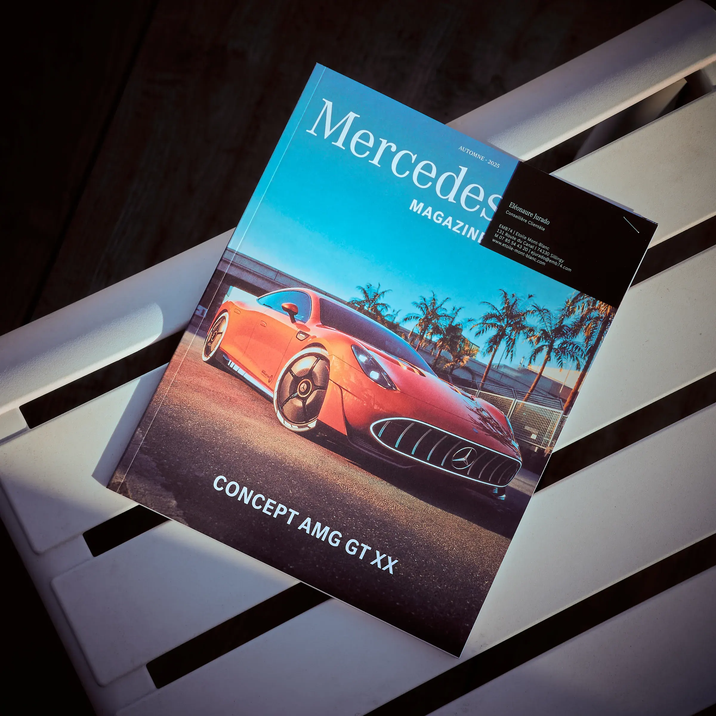 Magazine Mercedes-Benz automne 2025, Concept AMG GT XX orange en couverture, posé sur un banc blanc à Giez, photographie automobile