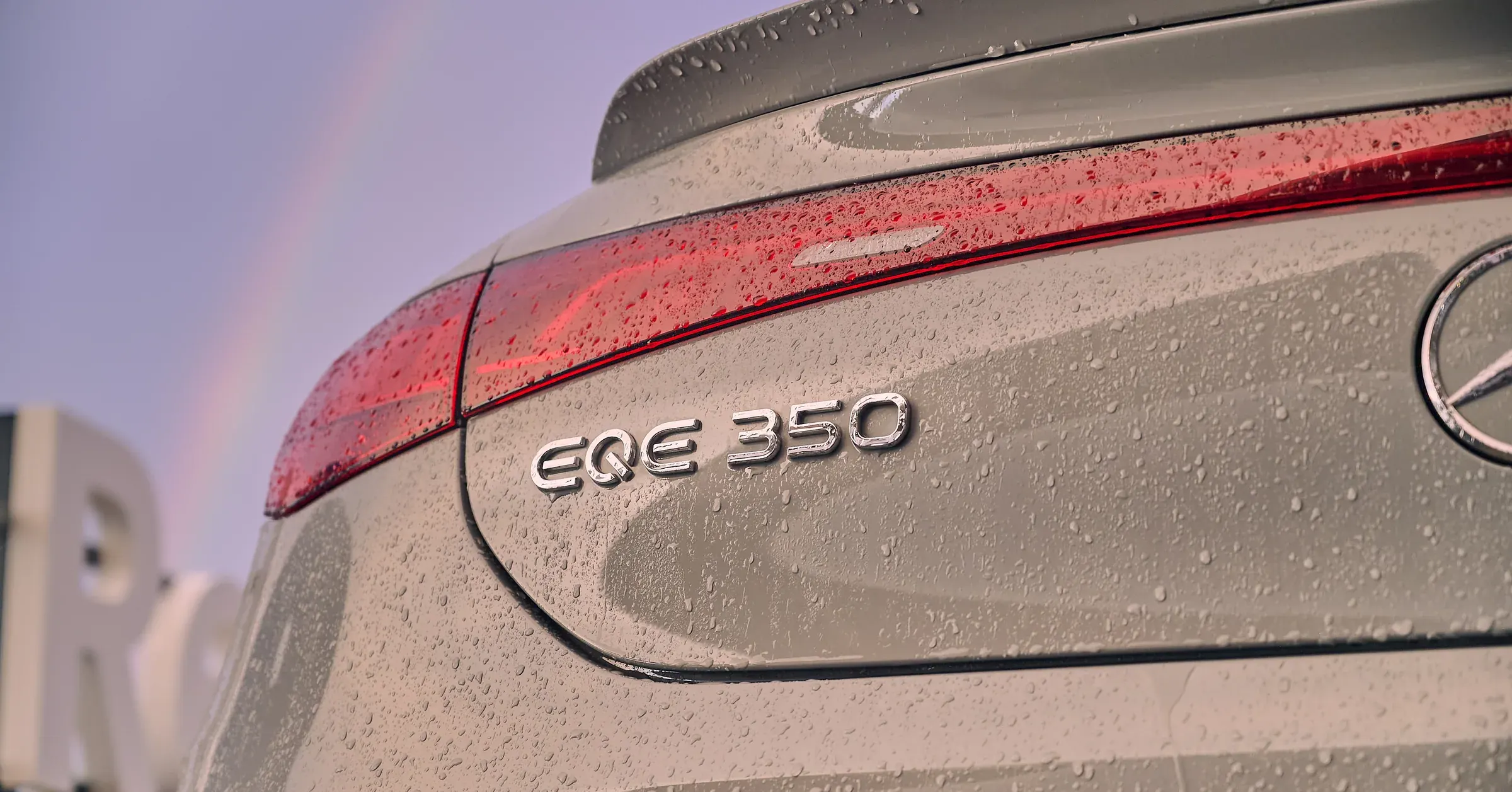 Monogramme EQE 350 et feux LED d'une Mercedes-Benz perlés de pluie sous un arc-en-ciel, photographe auto à La Roche-sur-Foron