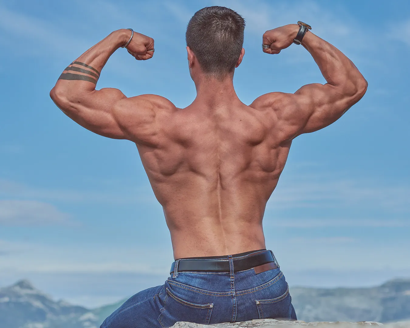 Bodybuilder de dos en double biceps dos exécuté en extérieur face aux montagnes, séance photo fitness