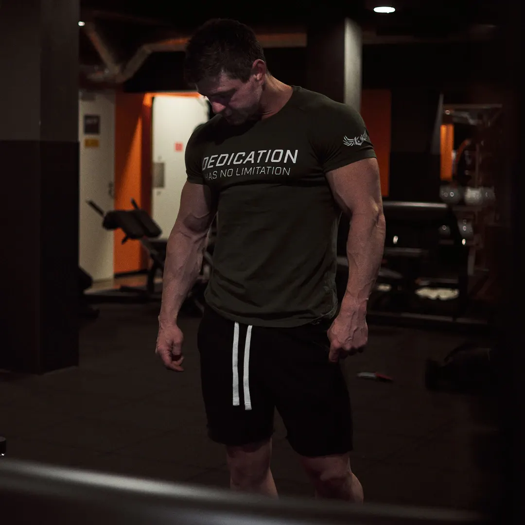 Athlète musclé en t-shirt « Dedication » dans une salle de sport, portrait fitness par un photographe à Genève