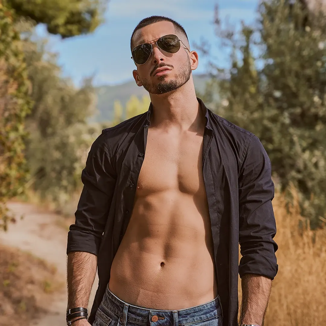 Athlète masculin torse sculpté, chemise ouverte et lunettes de soleil, séance photo fitness mode en extérieur sur la Côte d'Azur