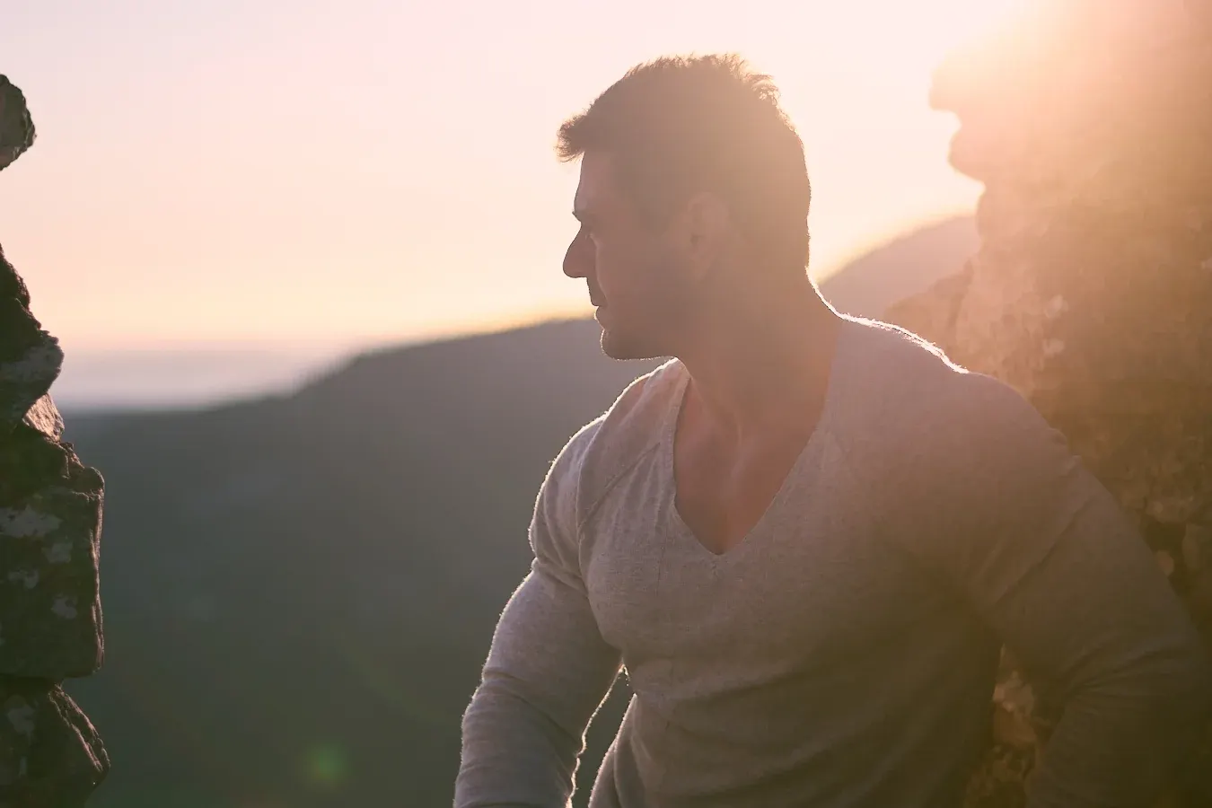 Athlète au profil musclé en haut d'un relief rocheux à contre-jour, séance portrait fitness en lumière dorée de coucher de soleil