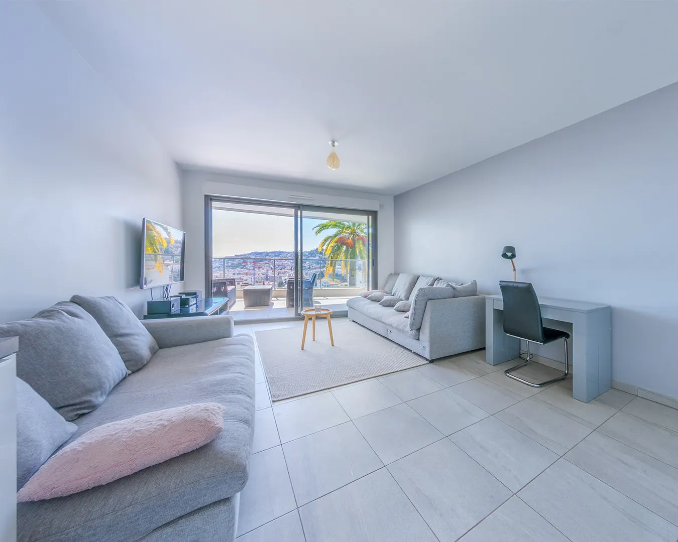 Séjour lumineux d'un appartement avec baie vitrée ouvrant sur la mer, photographie immobilière à Nice