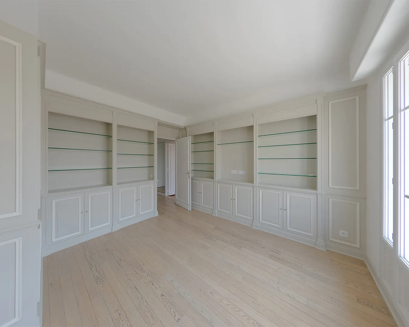 Salon haussmannien rénové avec bibliothèques intégrées et parquet clair, photographie immobilière à Nice
