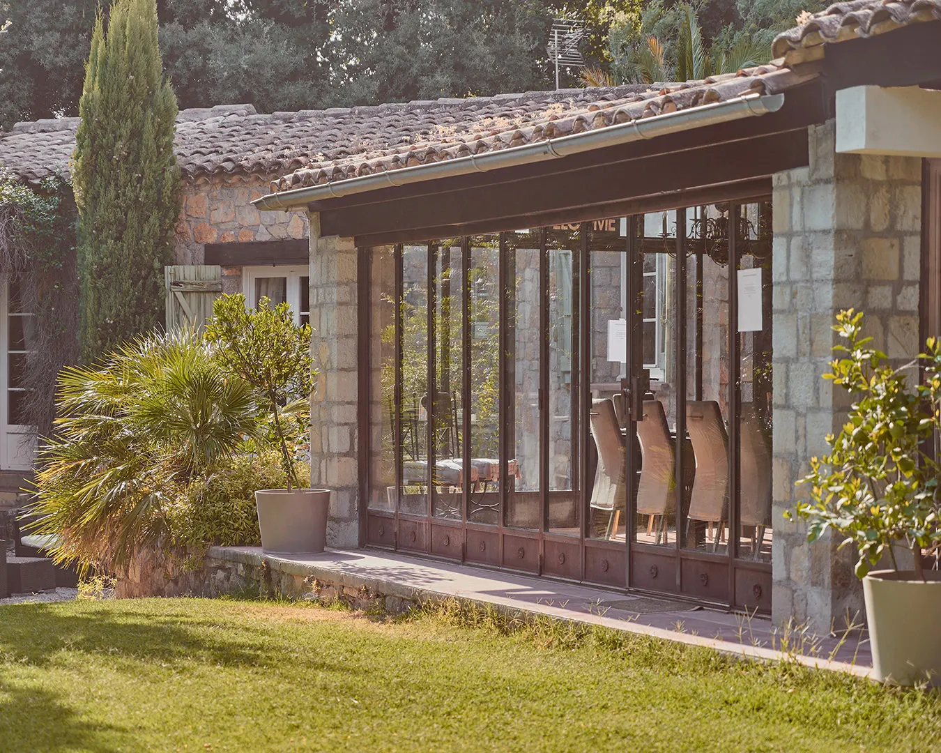 Véranda en verrière d'une villa provençale en pierre avec jardin, photographie immobilier haut de gamme sur la Côte d'Azur