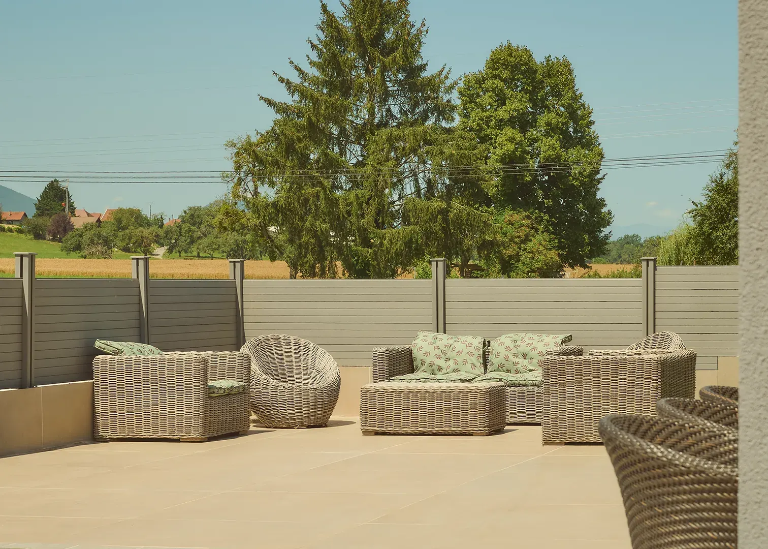 Terrasse aménagée avec salon de jardin en résine tressée face à la campagne, photographie immobilière en Suisse romande