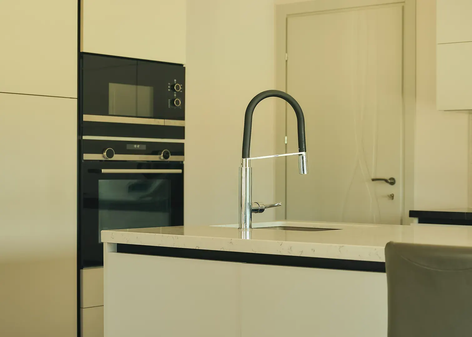 Cuisine contemporaine épurée : îlot en quartz, mitigeur design et four encastré, photographie immobilière haut de gamme
