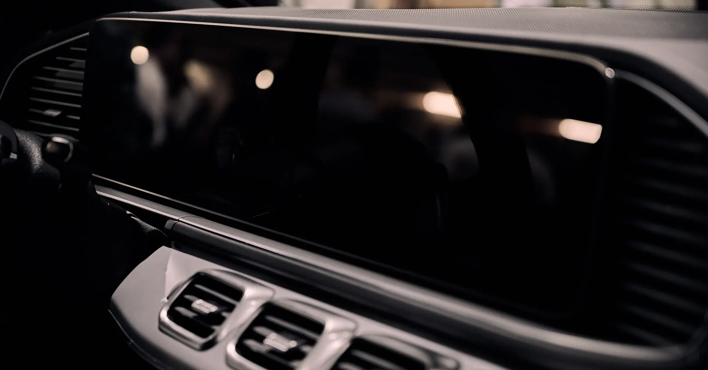 Planche de bord d’un SUV Mercedes-Benz, double écran noir et aérateurs chromés en clair-obscur, photographe automobile à La Roche-sur-Foron