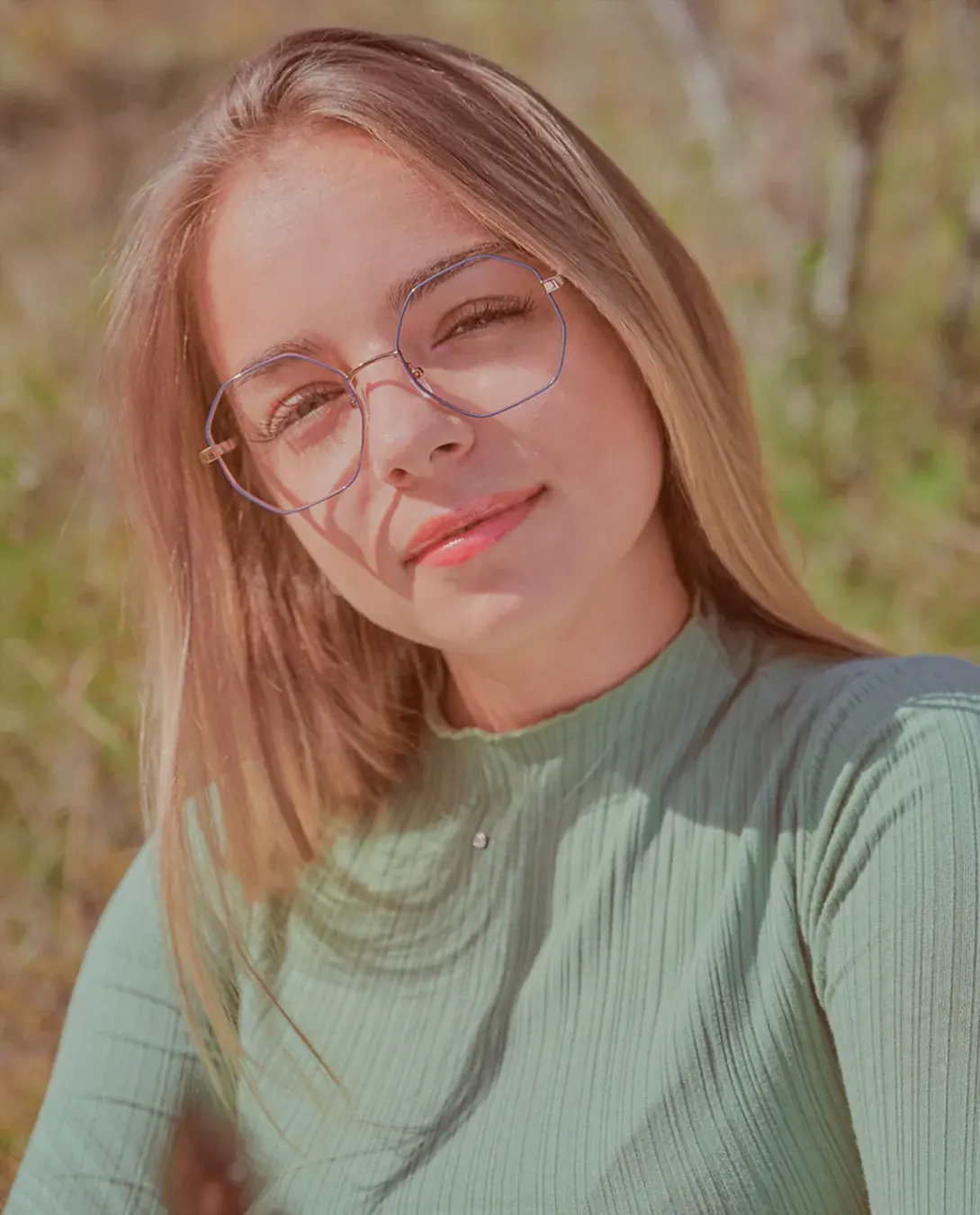 Portrait féminin en extérieur, lunettes fines et col montant vert d’eau, lumière naturelle chaude en fin de journée